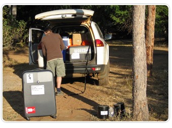 Dr. Inglis packing up for the road; lab ina box suitcase in foreground.