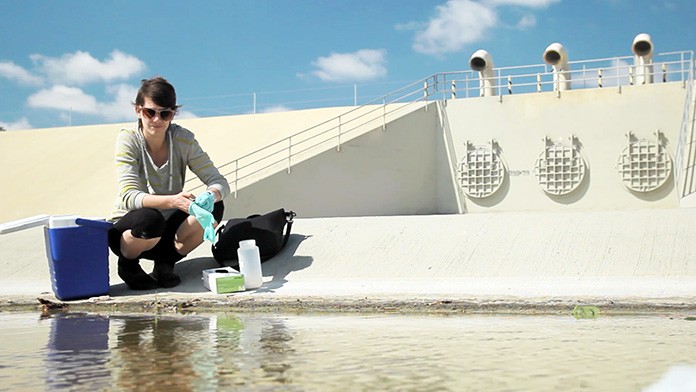 Scientist Meredith Raith collecting water sample from Santa Ana river for quality assessment using ddPCR